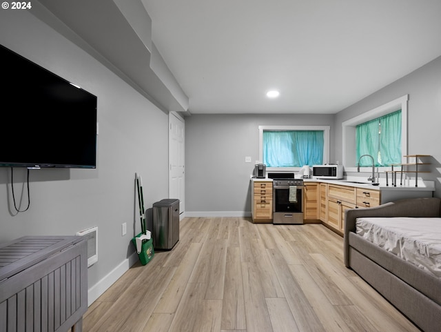 kitchen featuring light wood-type flooring, sink, stainless steel stove, and light brown cabinets