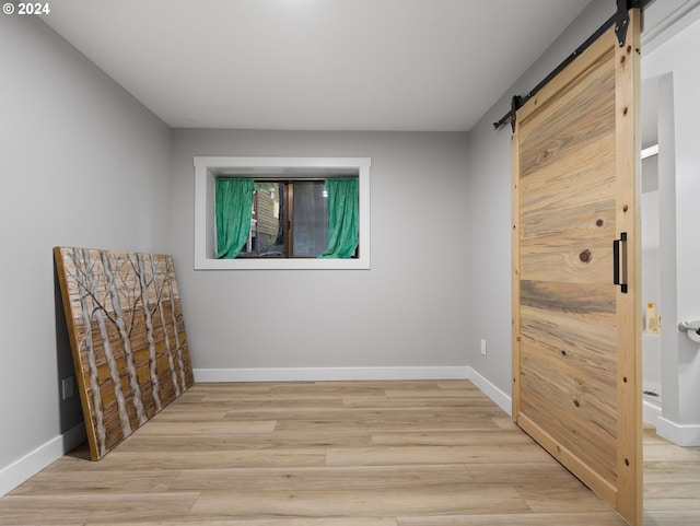 unfurnished room featuring a barn door and light wood-type flooring