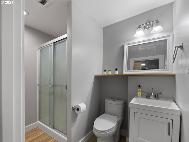 bathroom with a shower with door, vanity, hardwood / wood-style floors, and toilet