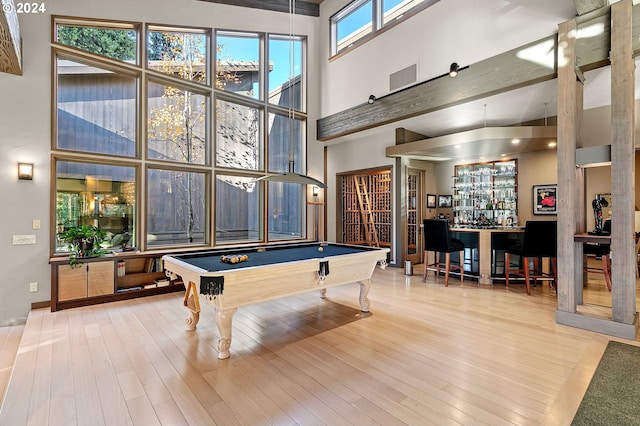 rec room featuring hardwood / wood-style flooring, a towering ceiling, billiards, and bar