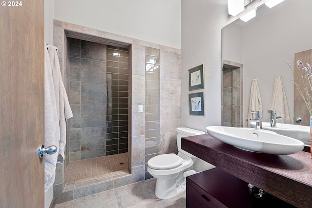 bathroom featuring a tile shower, vanity, and toilet