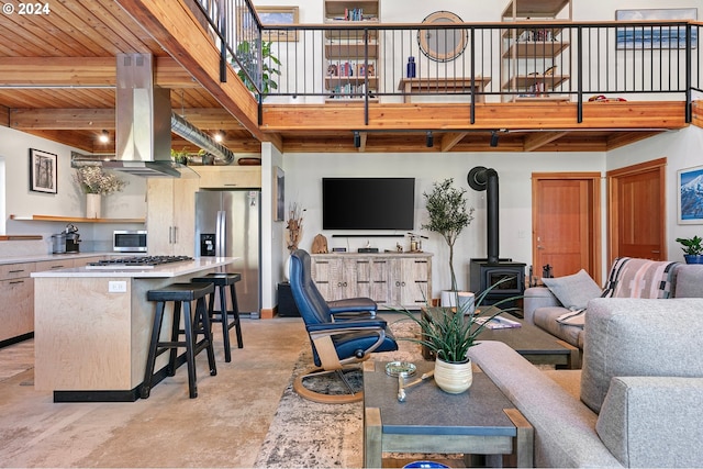 living room featuring a wood stove, beamed ceiling, and wood ceiling