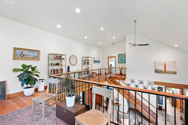 hallway with a healthy amount of sunlight, high vaulted ceiling, and light hardwood / wood-style floors