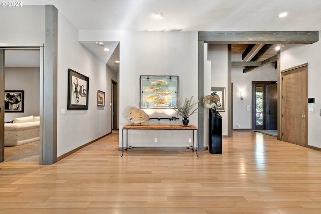 hallway with beamed ceiling and light hardwood / wood-style floors