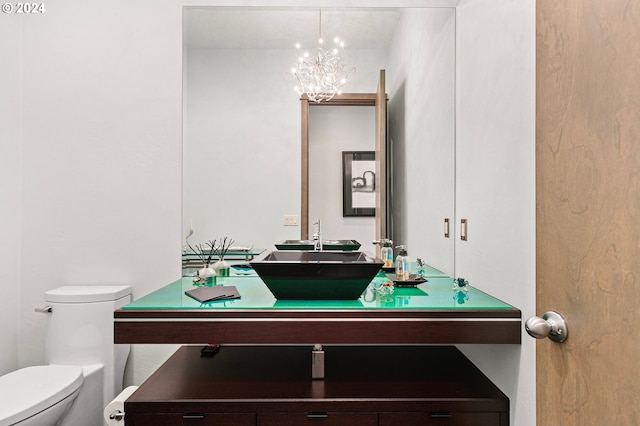 bathroom featuring vanity, an inviting chandelier, and toilet