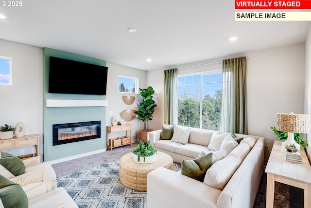 living area featuring carpet flooring, a glass covered fireplace, and recessed lighting