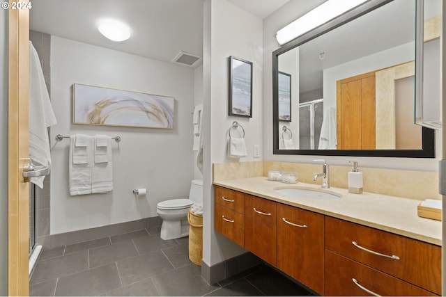 bathroom featuring tile patterned flooring, vanity, a shower with shower door, and toilet