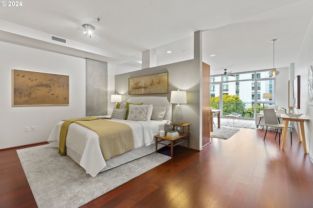 bedroom with expansive windows and dark hardwood / wood-style floors