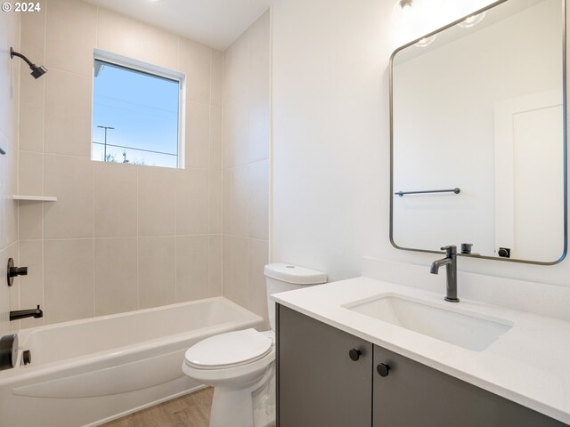 full bathroom featuring hardwood / wood-style flooring, vanity, tiled shower / bath, and toilet