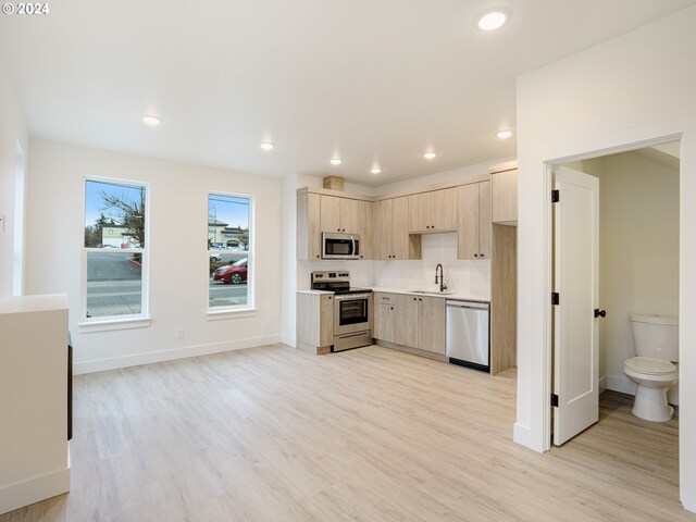 kitchen with stainless steel appliances, light hardwood / wood-style floors, sink, and light brown cabinets