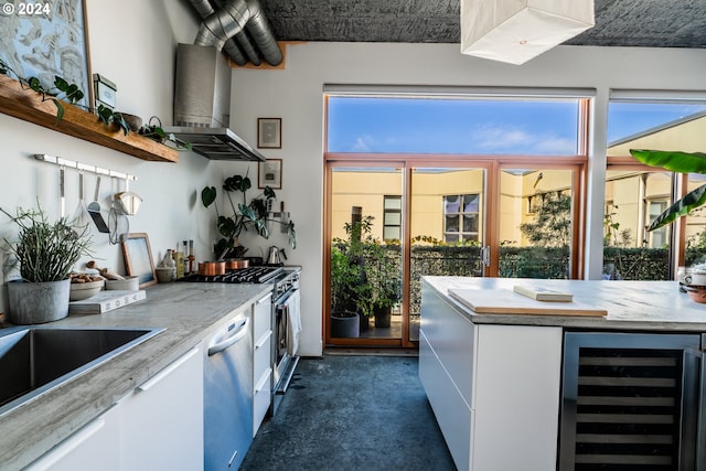 kitchen featuring white cabinetry, stainless steel appliances, beverage cooler, light stone counters, and ventilation hood