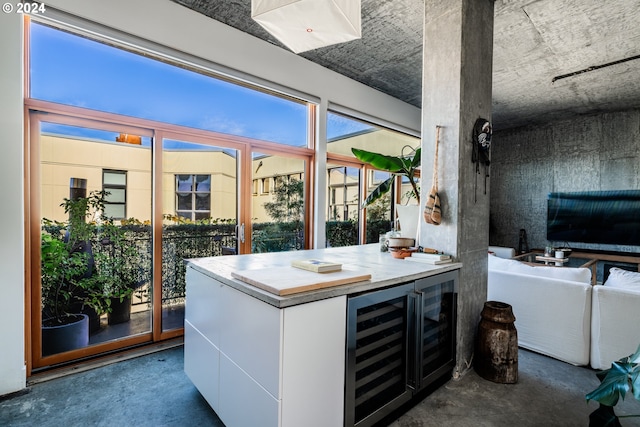 interior space featuring white cabinets, wine cooler, and concrete floors