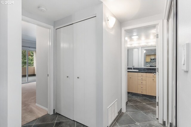 6605 W Burnside Rd Unit 144, Portland, OR 97210 - hallway featuring a sink, dark tile patterned flooring, and baseboards