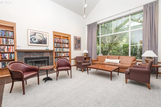 living area with a tiled fireplace, high vaulted ceiling, and carpet