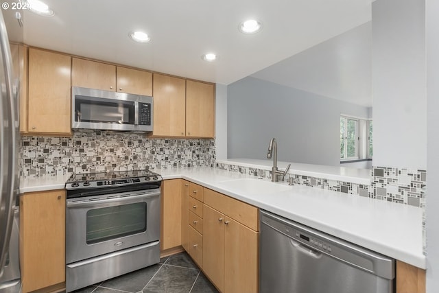 kitchen featuring tasteful backsplash, appliances with stainless steel finishes, light brown cabinetry, dark tile patterned flooring, and sink