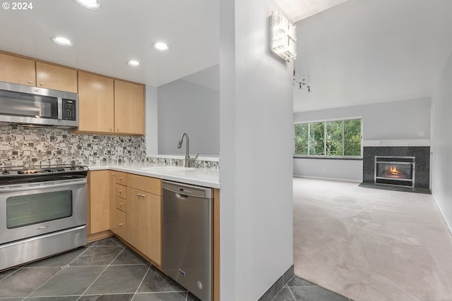 kitchen with dark carpet, sink, light brown cabinets, and stainless steel appliances