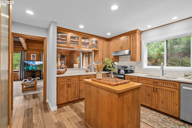 kitchen with appliances with stainless steel finishes, light hardwood / wood-style floors, wooden counters, a center island, and sink