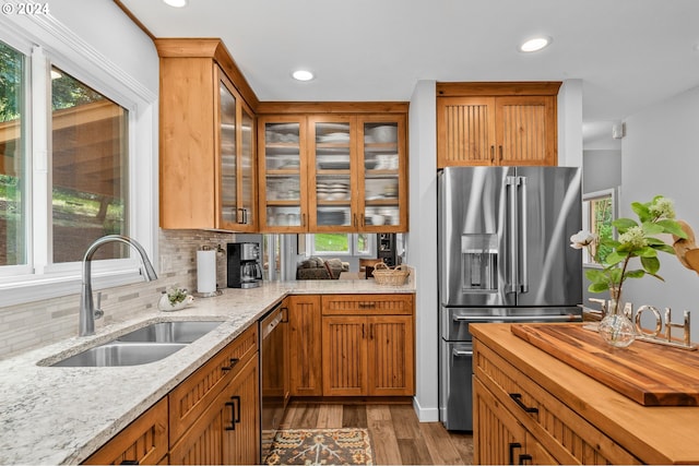 kitchen with stainless steel appliances, light hardwood / wood-style floors, a wealth of natural light, sink, and decorative backsplash