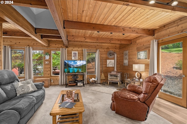 living room with a wood stove, beamed ceiling, and a healthy amount of sunlight