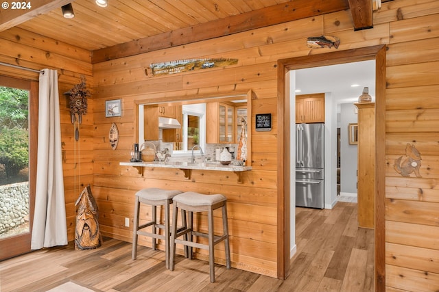 kitchen with backsplash, light wood-type flooring, wooden ceiling, and stainless steel refrigerator