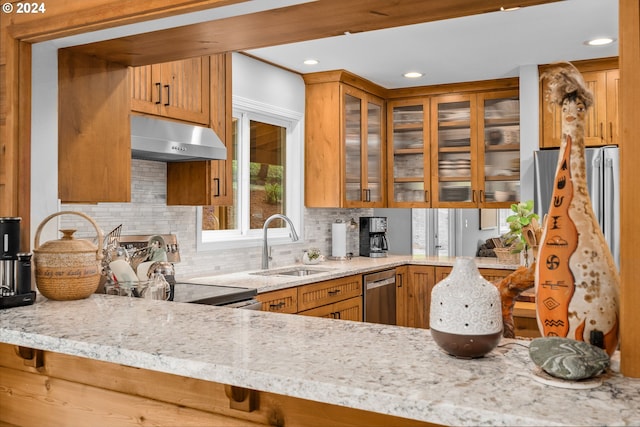 kitchen featuring kitchen peninsula, appliances with stainless steel finishes, wall chimney range hood, backsplash, and sink