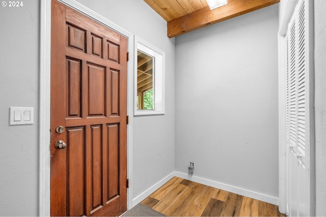 foyer entrance featuring beamed ceiling, light wood-type flooring, and wood ceiling