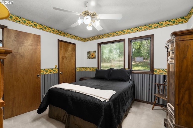 bedroom with a textured ceiling, light colored carpet, and ceiling fan