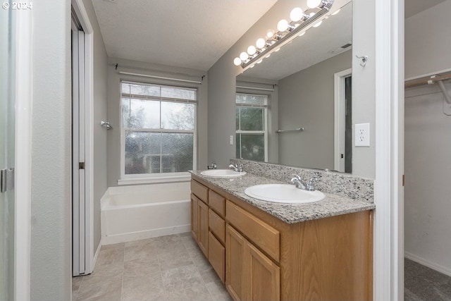 bathroom featuring a tub to relax in, vanity, and a textured ceiling