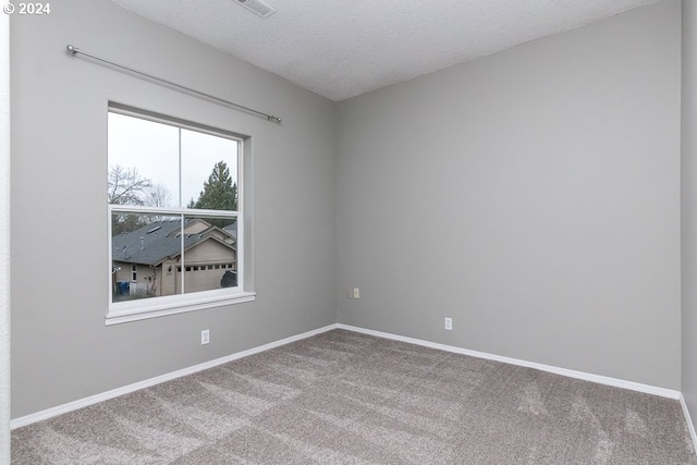 carpeted empty room featuring a textured ceiling