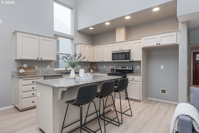 kitchen with white cabinets, a center island, light stone countertops, and appliances with stainless steel finishes