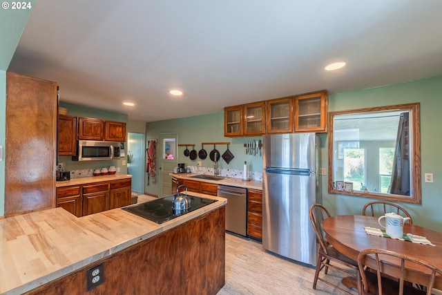 kitchen with kitchen peninsula, stainless steel appliances, sink, and light hardwood / wood-style floors