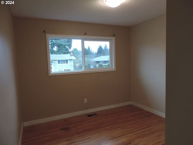 empty room with wood-type flooring and a textured ceiling