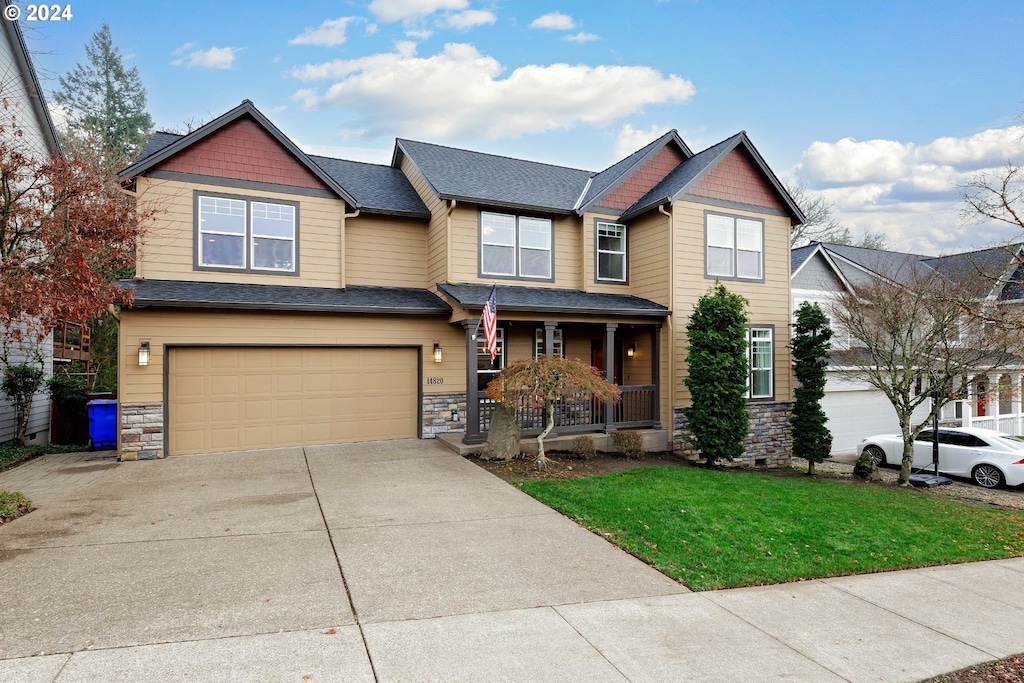 craftsman-style house featuring a front lawn, a porch, and a garage