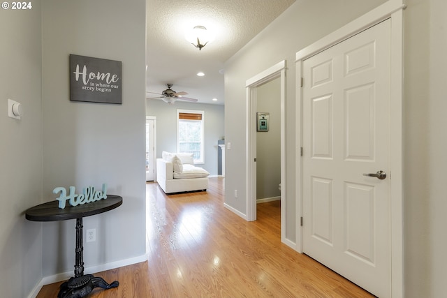 hallway featuring a textured ceiling and light hardwood / wood-style flooring