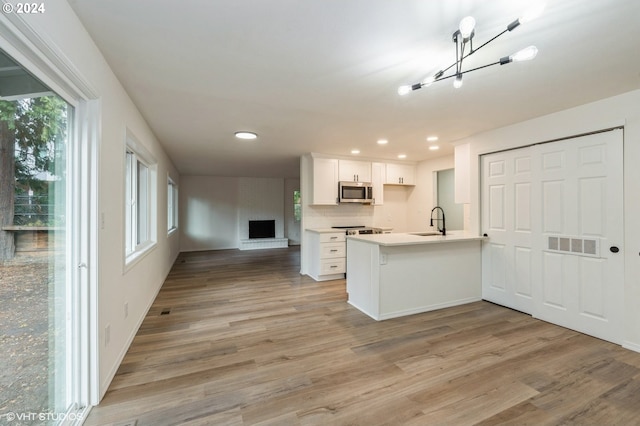 kitchen featuring kitchen peninsula, white cabinetry, plenty of natural light, and sink