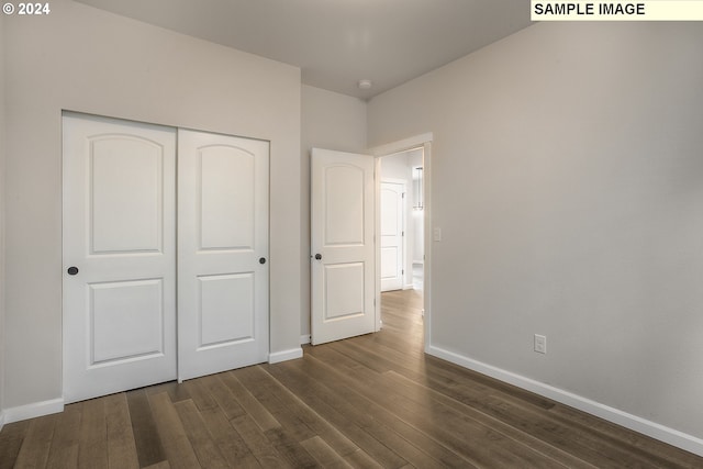 unfurnished bedroom with dark hardwood / wood-style flooring and a closet