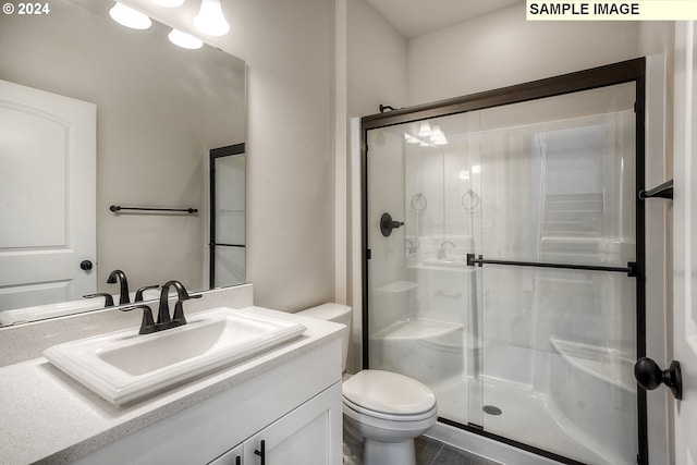 bathroom featuring tile patterned flooring, a shower with shower door, vanity, and toilet