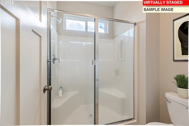 bathroom with toilet and a shower with shower door