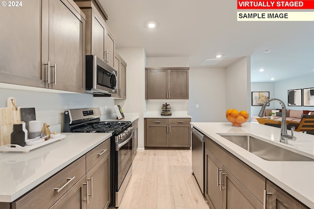 kitchen with appliances with stainless steel finishes, light hardwood / wood-style flooring, and sink