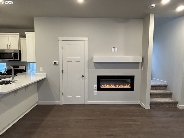 kitchen featuring appliances with stainless steel finishes, dark wood-type flooring, white cabinets, and a kitchen breakfast bar