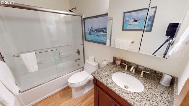 full bathroom featuring vanity, toilet, hardwood / wood-style flooring, and shower / bath combination with glass door