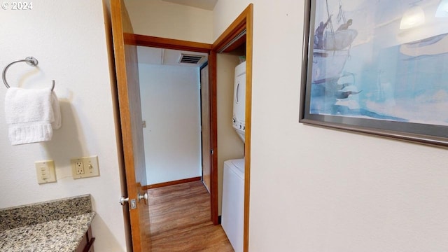 bathroom with vanity, toilet, stacked washer / dryer, and wood-type flooring