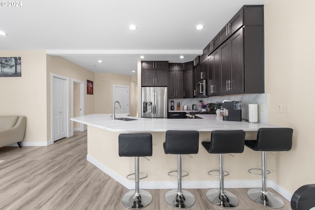 kitchen featuring sink, dark brown cabinets, a kitchen bar, kitchen peninsula, and stainless steel appliances