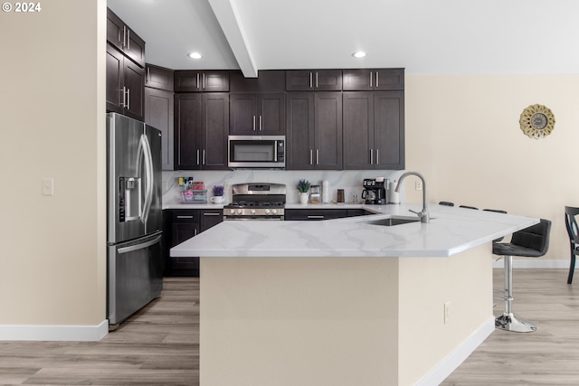 kitchen featuring beam ceiling, sink, stainless steel appliances, kitchen peninsula, and a breakfast bar