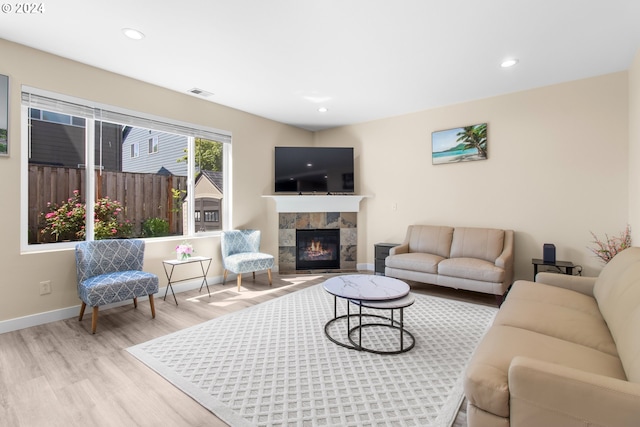 living room with light wood-type flooring and a tiled fireplace