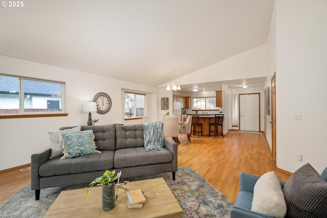 living area with an inviting chandelier, light wood-style flooring, visible vents, and a wealth of natural light