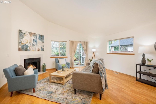 living room with light wood-style flooring, a fireplace, and vaulted ceiling