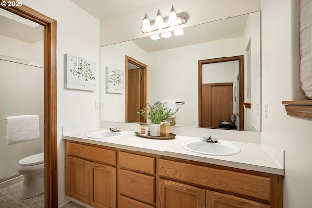 full bath with double vanity, toilet, and a sink