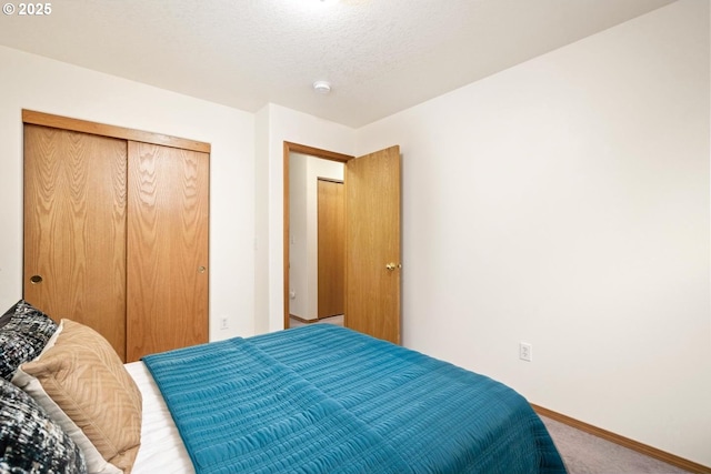 carpeted bedroom featuring a closet, baseboards, and a textured ceiling