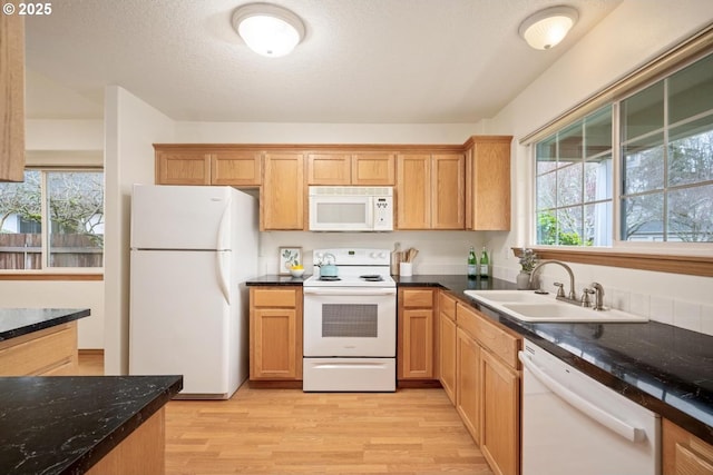 kitchen with a sink, white appliances, a wealth of natural light, and light wood finished floors